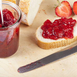 Homemade strawberry jam on white bread on a wooden board