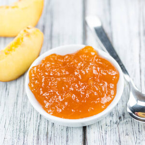 Peach jam (selective focus) on an old wooden table (close up shot)