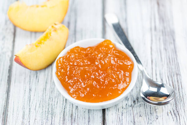 Peach jam (selective focus) on an old wooden table (close up shot)